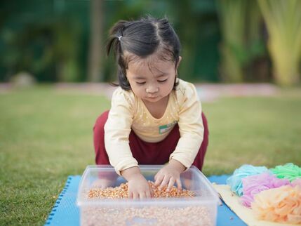 A small girl with her hands in a box 