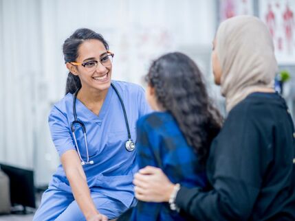 A doctor sitting with a child and her mother