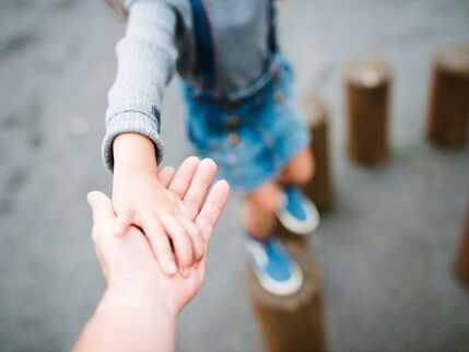 Childs hand being supported by adult hand 