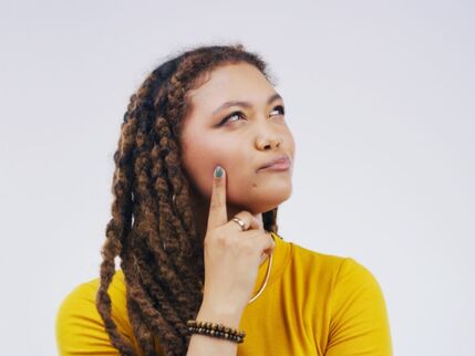 A woman pondering in a yellow jumper 
