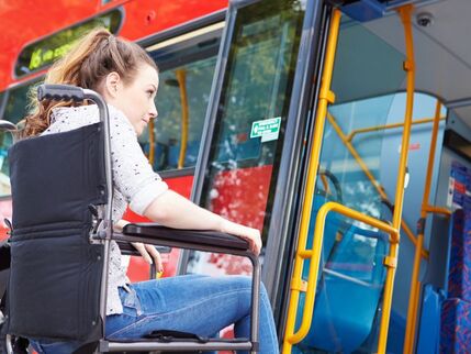 Girl in a wheelchair getting on a red bus